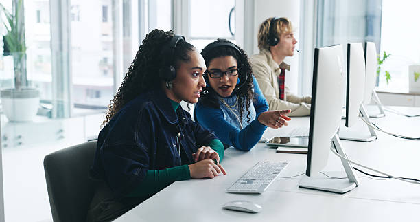 istock Teamwork, computer or people with advice in call center for training question, online system or help. Telemarketing trainee, coworking or agent pointing for sales assistance, CRM or product knowledge 2233807730