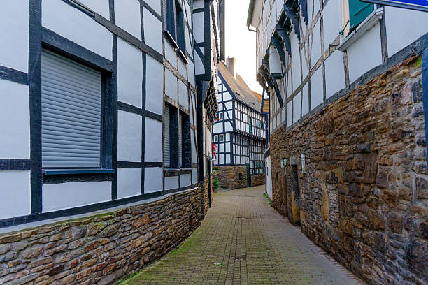 Narrow cobblestone alleyway flanked by half-timbered houses and stone walls in Hattingen, Germany.