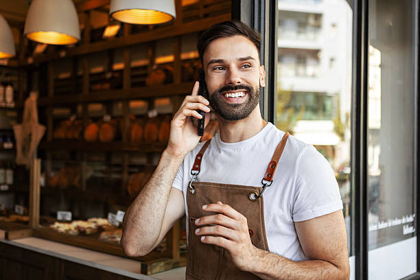 istock Cheerful young bakery owner talking on phone in shop 2233809009