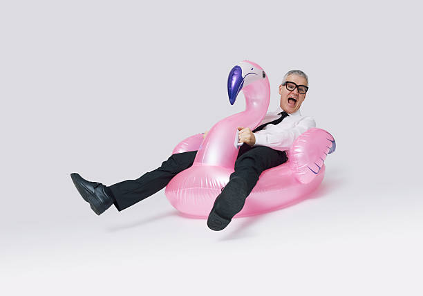 istock Cheerful business executive riding an inflatable flamingo 2233809124