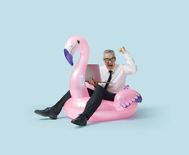 istock Cheerful businessman riding an inflatable toy and using a laptop 2233809415