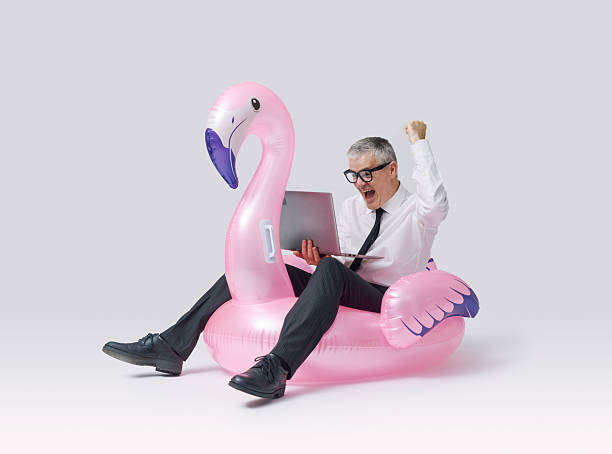 istock Cheerful businessman riding an inflatable toy and using a laptop 2233809545