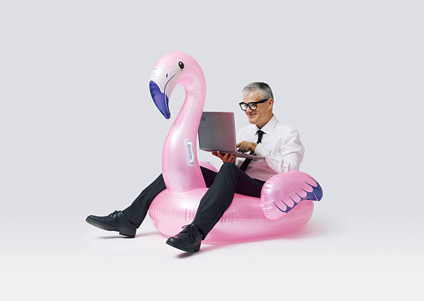 istock Cheerful businessman riding an inflatable toy and using a laptop 2233809589