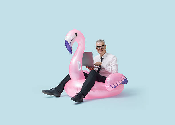 istock Cheerful businessman riding an inflatable toy and using a laptop 2233809642