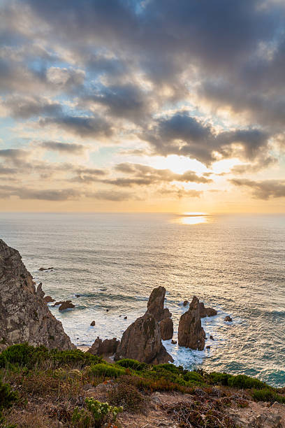 istock A dramatic coastal scene with towering sea stacks, rugged cliffs, and lush greenery under a golden-hued sky 2233811258