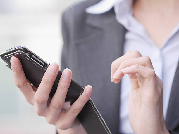 istock Woman is holding a cell phone in her hand while wearing a suit 2233811622