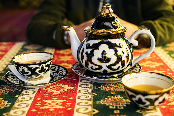 istock Traditional tea ceremony setup with a beautifully patterned Uzbek teapot and cups on a colorful, vibrant table runner, with a person sitting discreetly in the background 2233812501