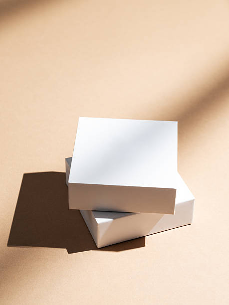 istock Two white square boxes on a beige background with natural light and shadows. 2233814435