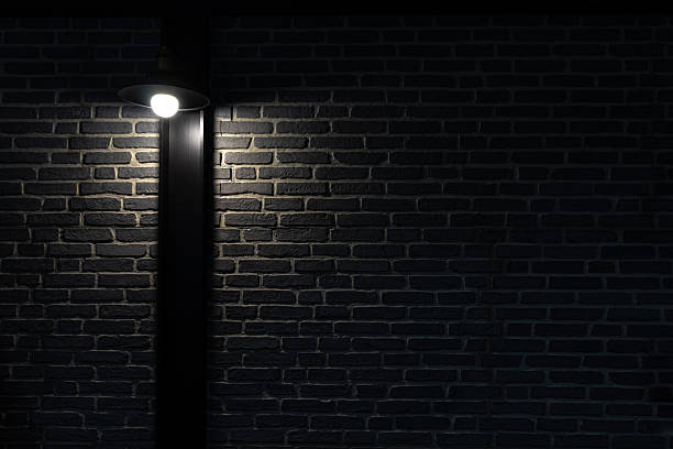 istock Wall light on black brick wall. Dark brick wall with lamp above. 2233815918