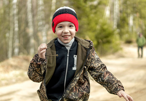The cute boy is walking at rural area on the path. Shooting in countryside at in sunny spring day