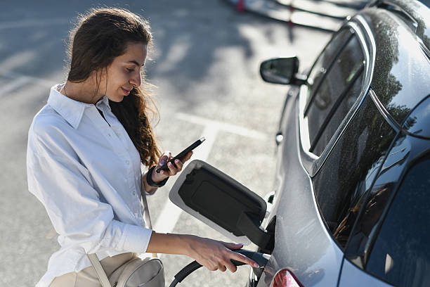 istock Woman Checking Messages on Phone While Waiting for EV to Charge 2233823030