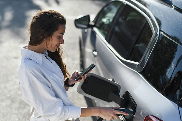 istock Female Driver Texting While Her Electric Car is Powering Up 2233823112