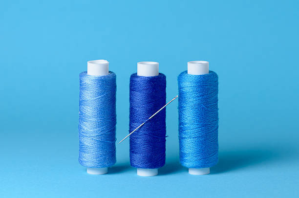 istock Row of blue thread spools with needle aligned background with copy space for text close-up flat lay top view 2233823116
