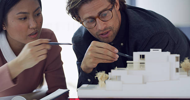 istock Architecture, planning or teamwork for 3D model of building review in office for construction project. Engineers, prototype design or people in meeting for development, real estate or mini property 2233825408