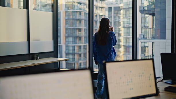 istock Confident woman calling mobile phone having positive conversation office window 2233827246