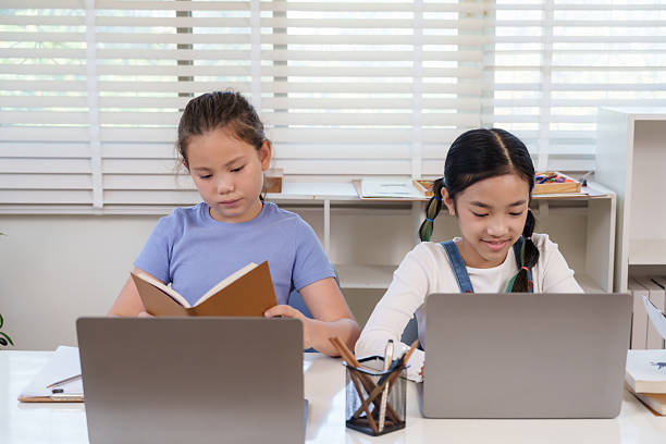 istock Caucasian preteen girl reading notebook beside asian classmate using laptop during classroom teamwork activity representing education creativity learning friendship digital literacy project 2233829564