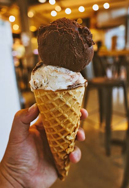 istock Hand Holding Ice Cream Cone with Chocolate and Vanilla Scoops 2233830244