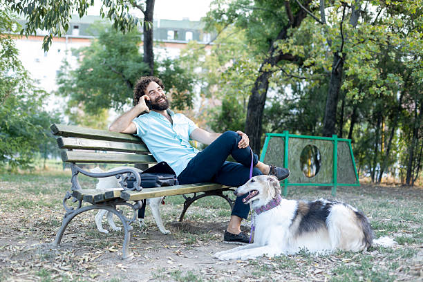 Man with his pet Borzoi (Russian hunting sighthound) in a dog park. About 45 years old, Caucasian male.