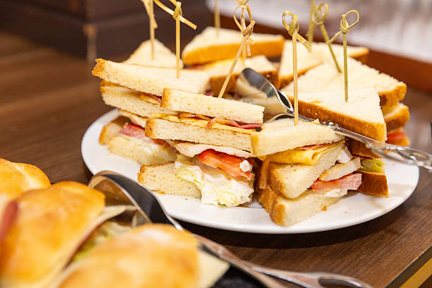 Tramezzino sandwiches stacked in a plate, served with skewer pierced through the middle, savory cold table food