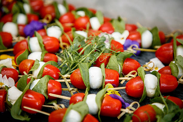 Close-up on cherry tomato and mozzarella with arugula leaves on skewers served on buffet, cold table food