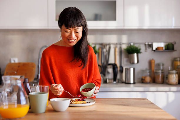 istock Woman adding berries to waffles while having breakfast at home 2233832180