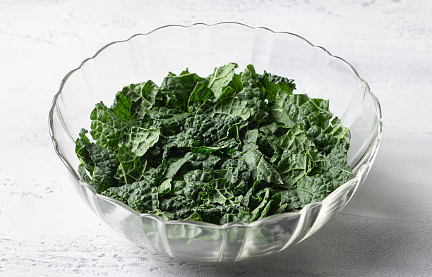 Fresh chopped kale leaves in glass bowl on white kitchen table