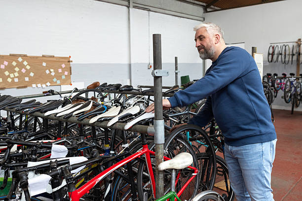 Male volunteer working in a warehouse designed for bike recycle/reuse. He is looking over a stand housing multiple bikes. He is in Newcastle Upon Tyne.Videos are available similar to this image.