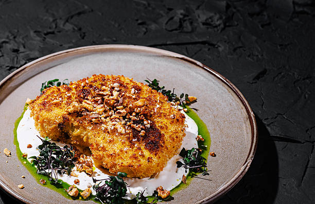 istock Gourmet breaded cutlet with nuts, microgreens, and sauces on a ceramic plate 2233833377