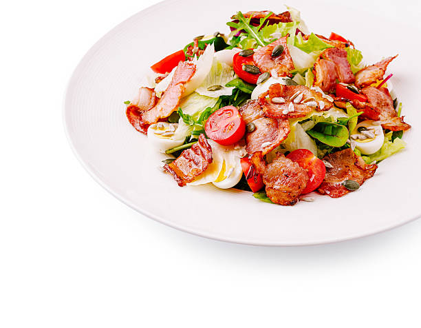 A vibrant salad displays a mix of crispy bacon, fresh greens, and bright red cherry tomatoes. This colorful dish is perfect for a light meal or appetizer.