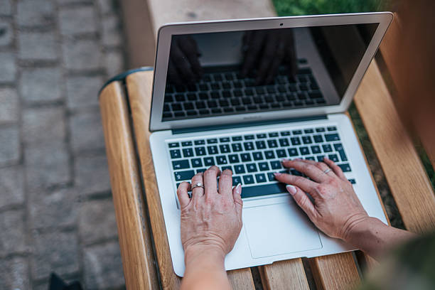 Woman working on laptop outdoors on wooden bench
