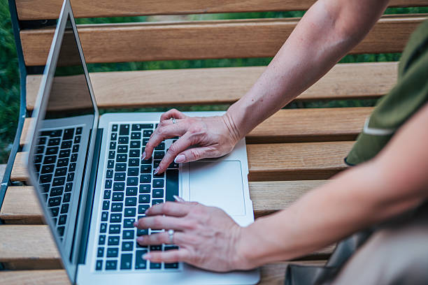 istock Woman working on laptop outdoors on wooden bench 2233836016