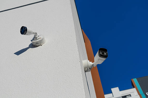 istock Two security cameras are installed on a white exterior wall of a building, providing surveillance on a sunny day 2233836747
