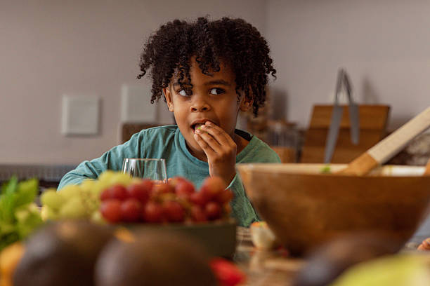 Cute black child eating a chocolate cookie with his father