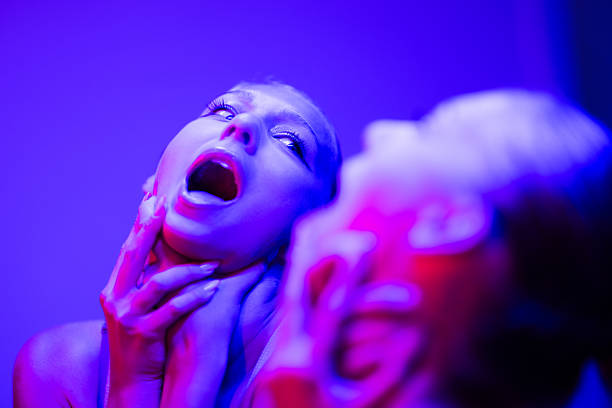 Young woman strangles herself and screams under a colorful neon lights.