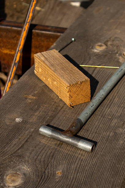 Close-up of hand tools and raw timber on weathered planks, depicting traditional, rustic log house construction.