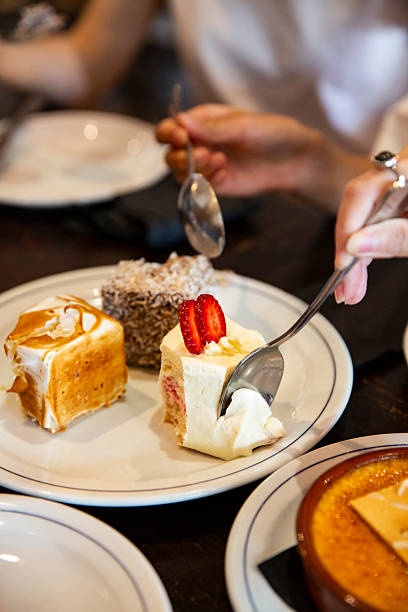 istock Hands sharing assorted mini cakes lamington caramel square and strawberry shortcake on white plate 2233838780