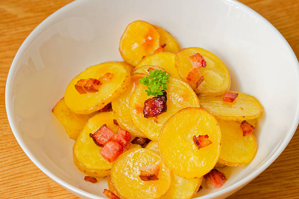 Tasty baked sliced potatoes with bacon in bowl