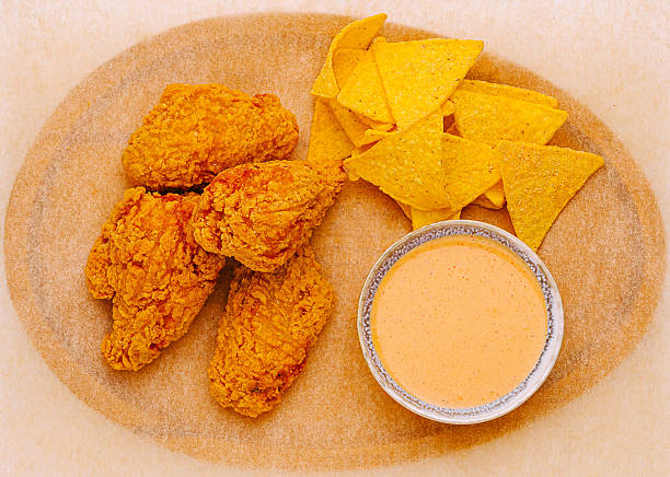 Crispy fried chicken served with tortilla chips and spicy sauce on a platter