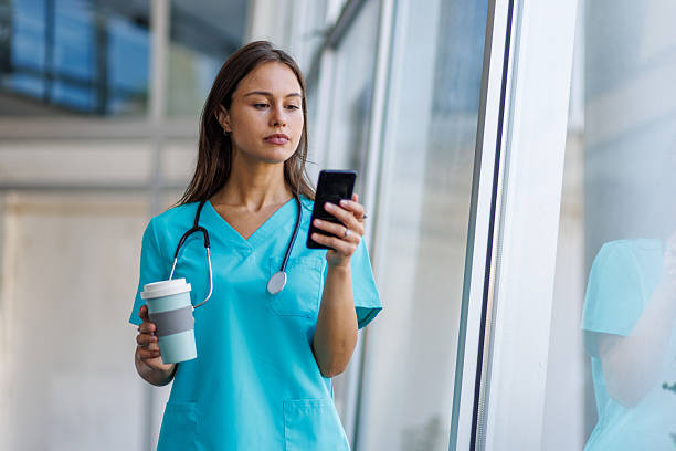 istock Young nurse walking and using smartphone in hospital corridor 2233843490