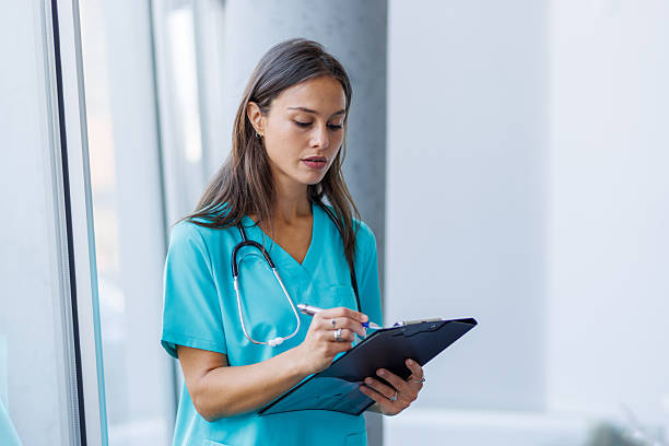 istock Young nurse taking notes on clipboard in hospital corridor 2233843555