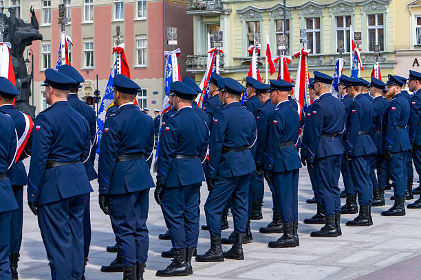 Bydgoszcz, Kuyavian-Pomeranian Voivodeship, Poland - july 15, 2025 Uniformed police officers standing in formation with ceremonial banners, Police Day celebration on city square with historic buildings background