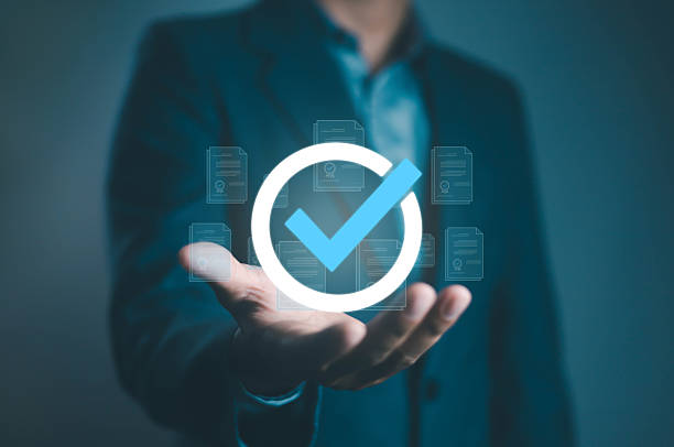 istock Businessman holding a digital check mark icon representing approval, validation, quality assurance, and certification in modern business technology and document management concept. 2233849173