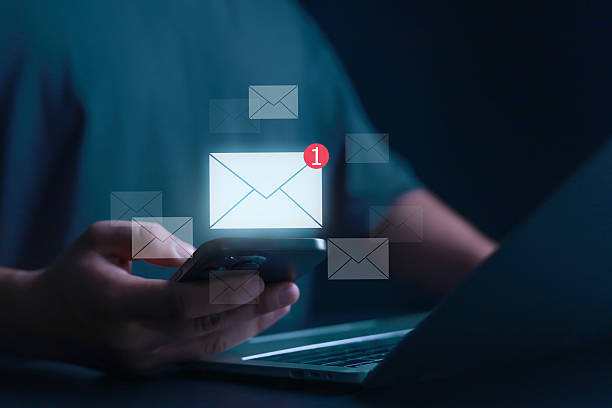 istock Hand holding smartphone with glowing email notification icon, symbolizing new message, online communication, inbox, mobile app, business connection, digital marketing, and internet technology concept. 2233850490