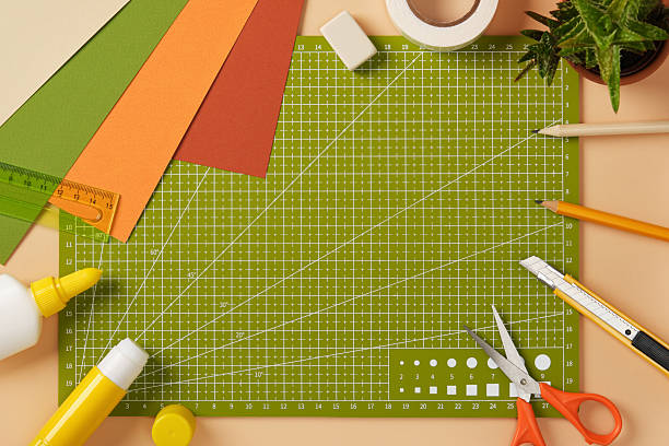 istock Creative mess on the paper crafting table. Colored sheets of paper, glue, pencils, eraser, scissors, and knife on a cutting mat. 2233854885