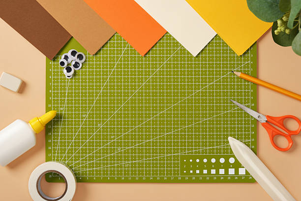 istock Green cutting mat surrounded by colored paper and crafting tools on a table. Creative workspace for arts and crafts. 2233854948