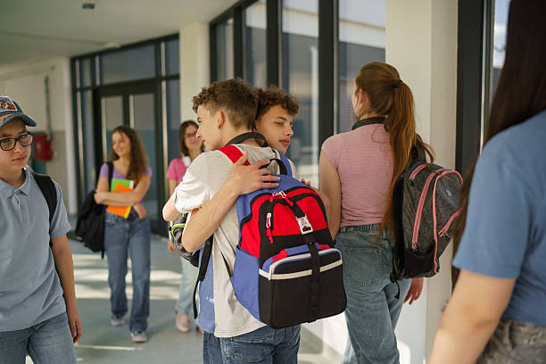 istock Teenage students hugging in school hallway 2233859679