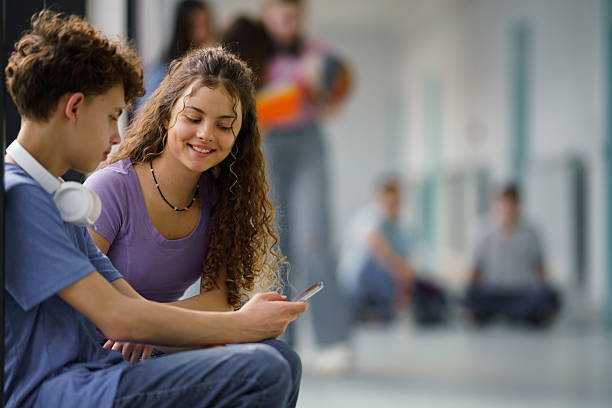 istock Teenage students sharing mobile phone at school corridor 2233860566