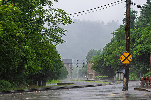 A rainy landscape of Thurmond, West Virginia in the rain with rail crossing and historic buildings.