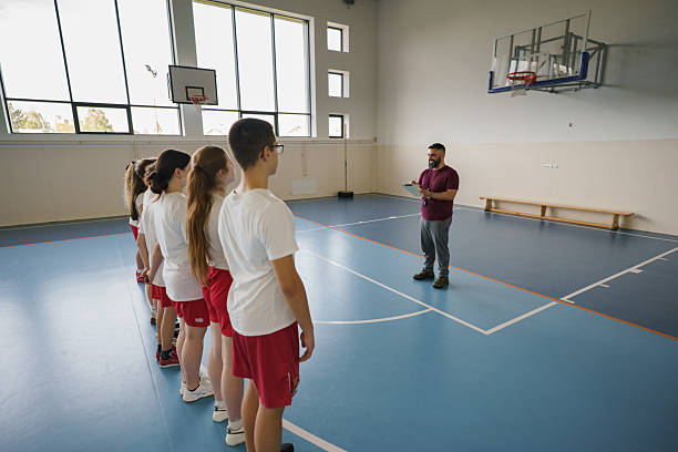 Group of high school students listening to their coach on the basketball court