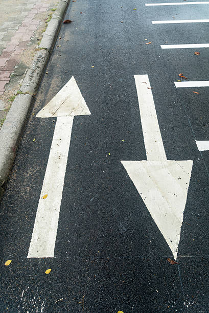 istock Directional Arrows on Wet Asphalt Road 2233872720